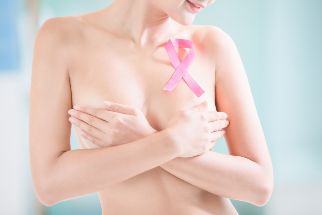 kobieta zasłaniające swoje piersi z różową wstążką